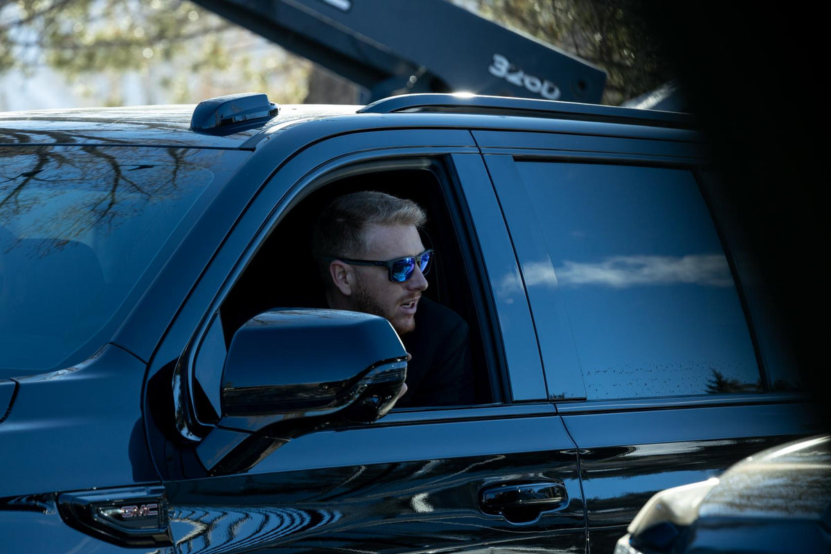 Chauffeur in sunglasses at the wheel of a black SUV fitted with a roof ski rack